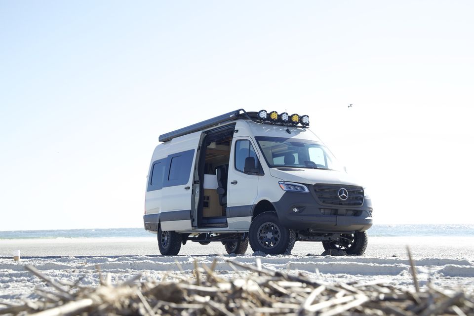 A white Sprinter camper van on the beach