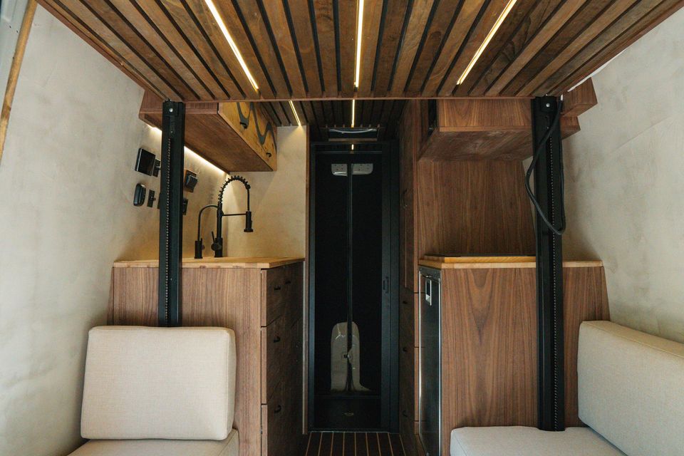 A walnut slat ceiling over a lounge and a glass shower