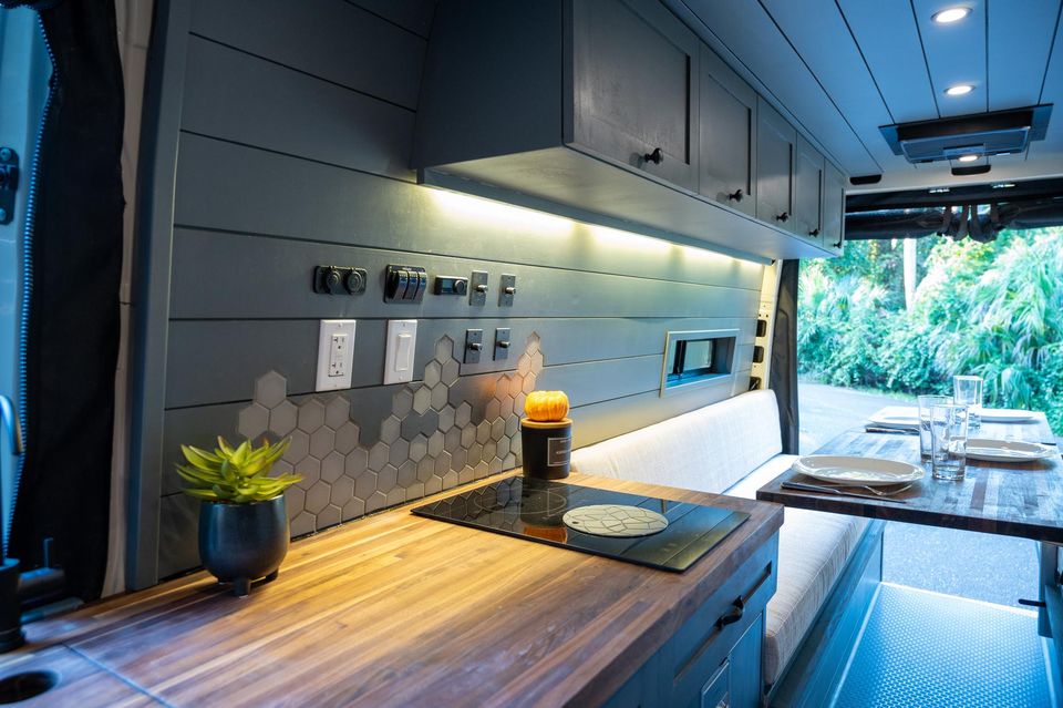 A dark cabinet kitchen with a butcher-block counter