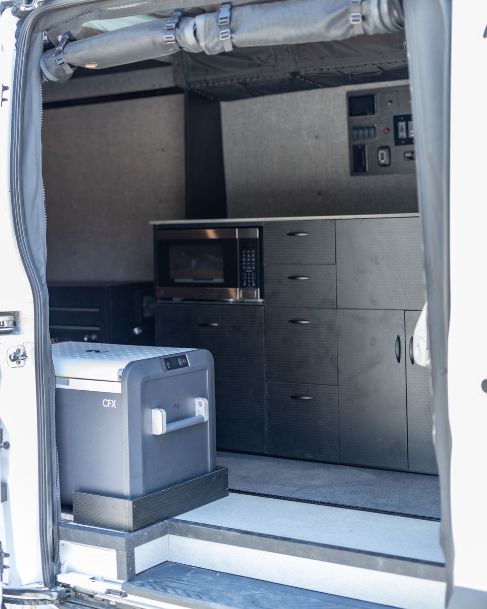 A fridge and control panel inside a custom Transit