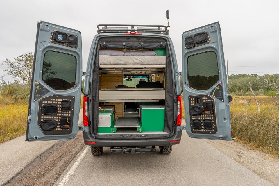 A Sprinter with the rear doors open to a garage of gear bins