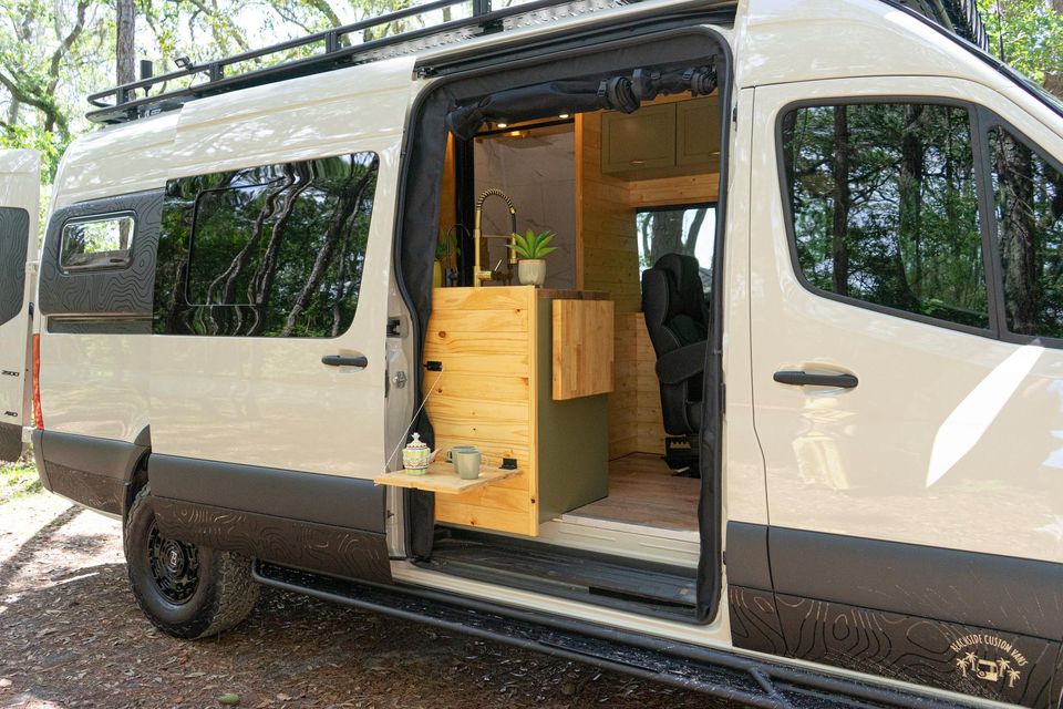 A white Sprinter with the sliding door open to a wood interior