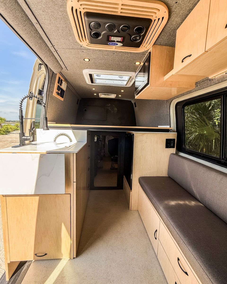 Gray upholstered panels and a marble counter in a custom Sprinter