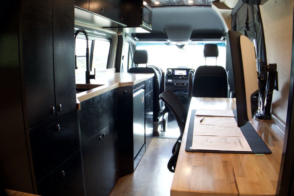 The Gamer Van interior looking forward past the galley and desk to the cab seats