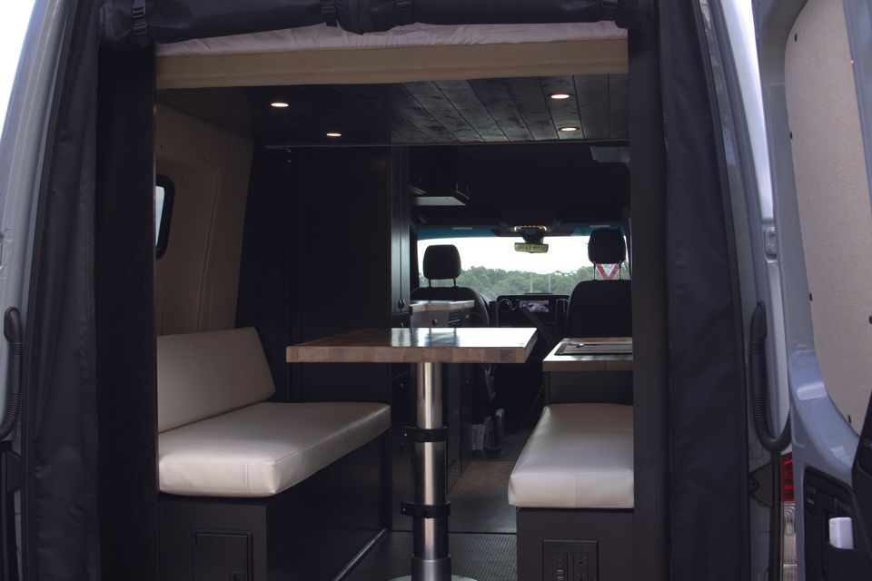 The Gamer Van lounge, bench seating and table seen from the open rear doors