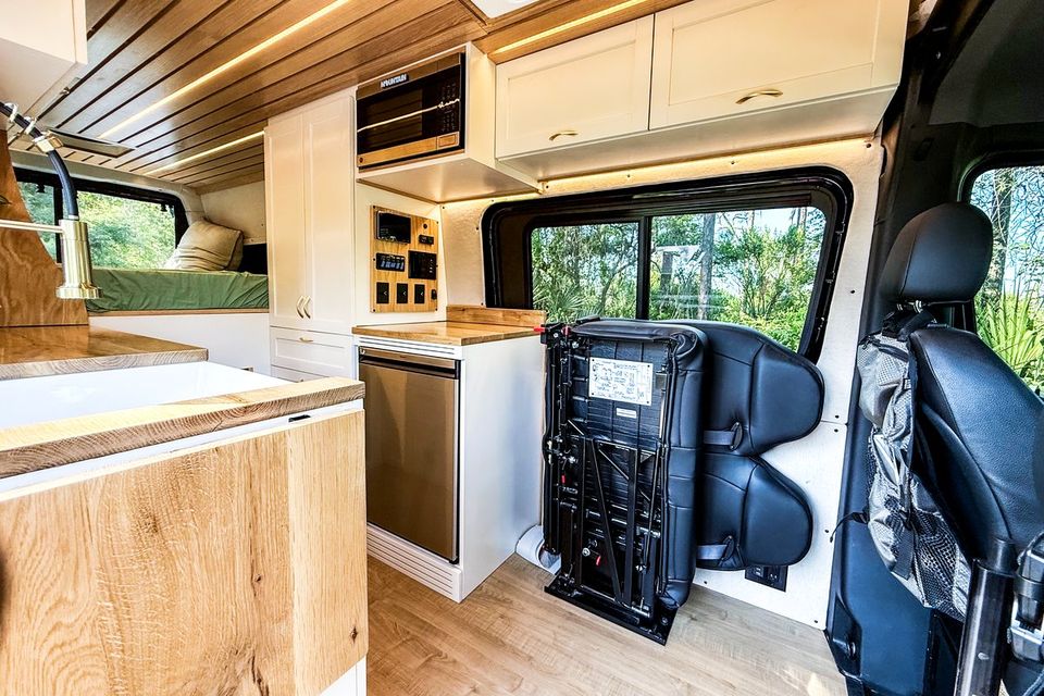 A van interior with a galley, swivel seat and cabinetry