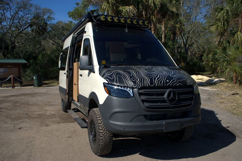 A white Sprinter with a black patterned vinyl wrap on the hood